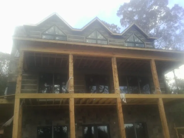 Dormers and porch framing on a large log home under construction — Roof Coating work by our crew in Merrill