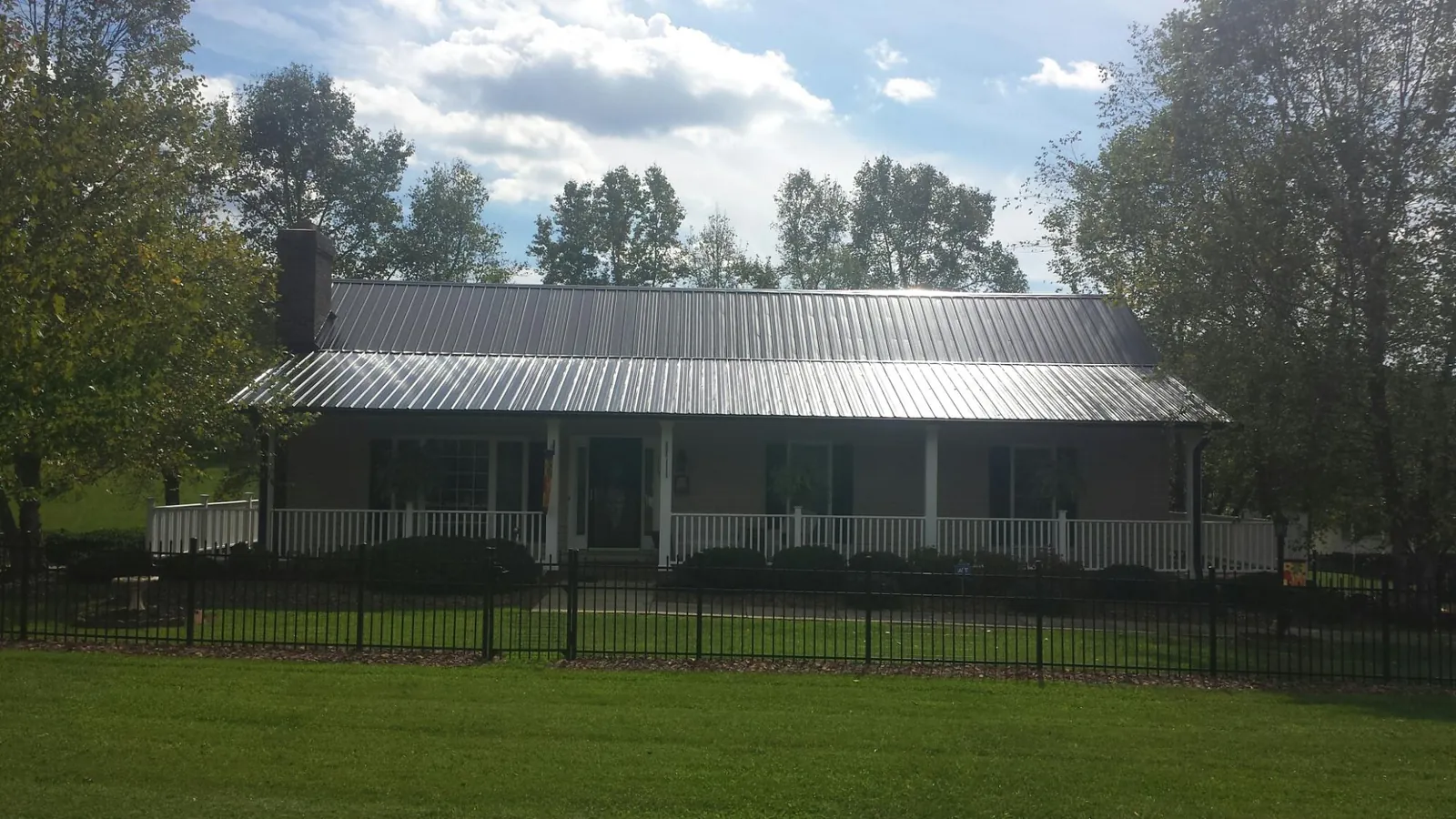 Gray metal roof on a brick ranch with a full width front porch — Gutter Guard Installation work by our crew in Merrill